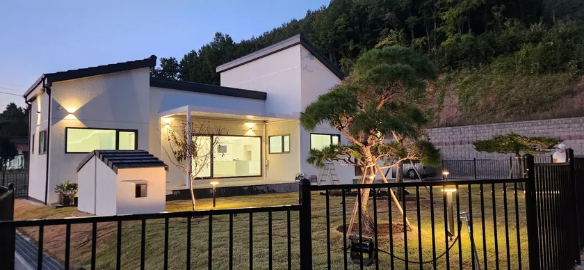 저녁빛 아래 불을 밝힌 사애헌의 경사지붕과 마당